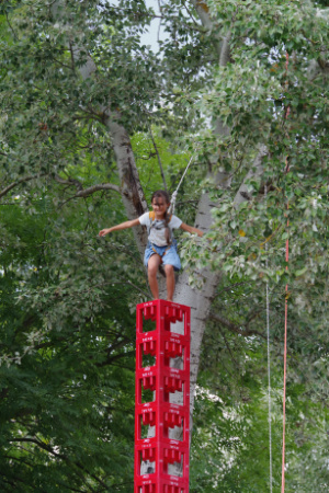 Ein kleines Mädchen, dass auf einem hohen Turm aus aufgestapelten Cola-Kisten geklettert ist.