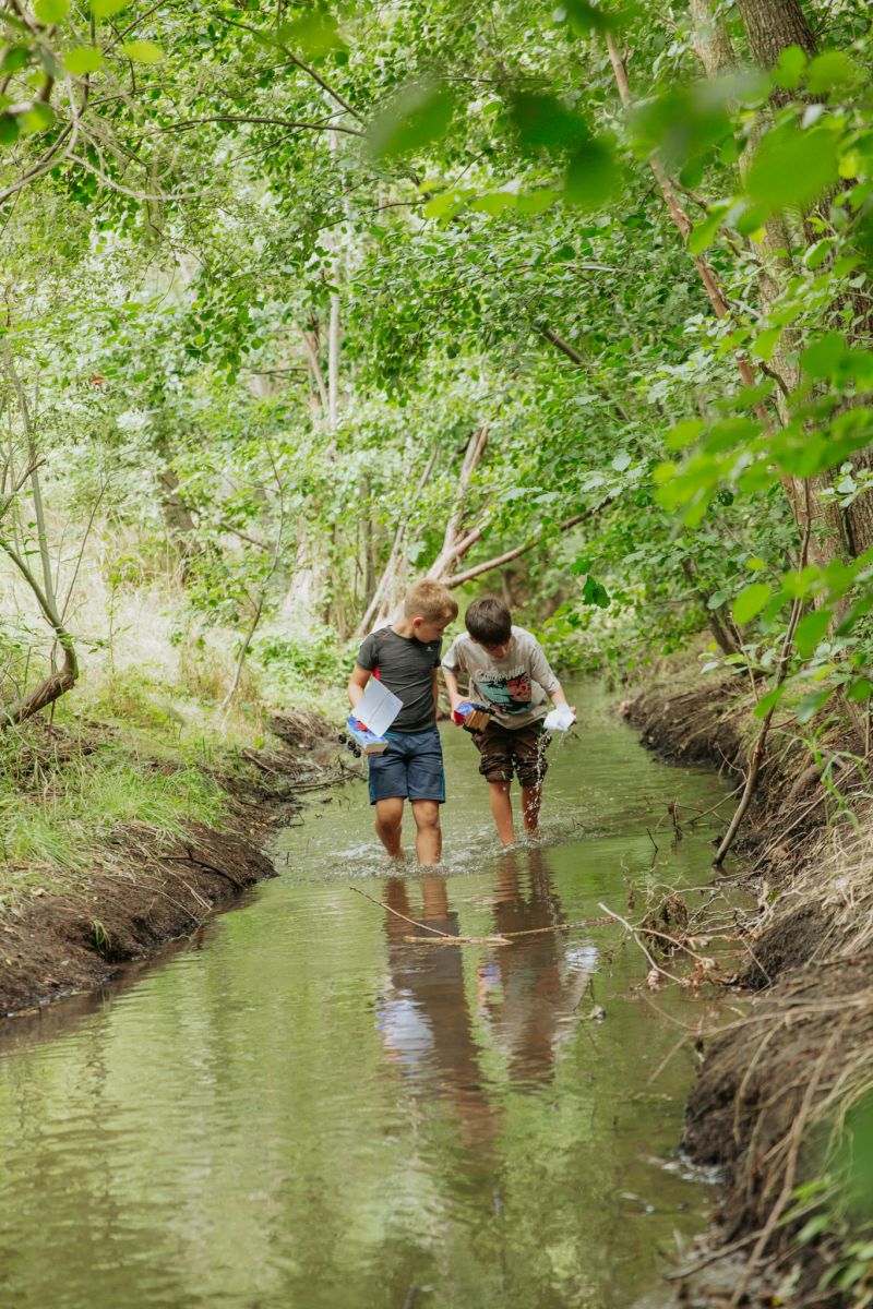 Ein kleines Mädchen, dass auf einem hohen Turm aus aufgestapelten Cola-Kisten geklettert ist.