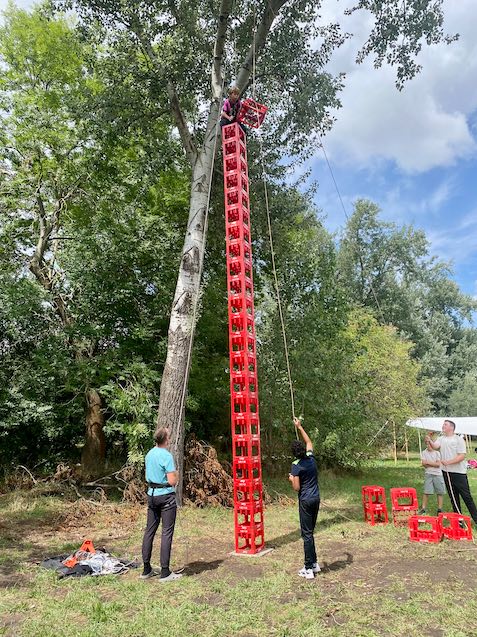 Ein kleines Mädchen, dass auf einem hohen Turm aus aufgestapelten Cola-Kisten geklettert ist.